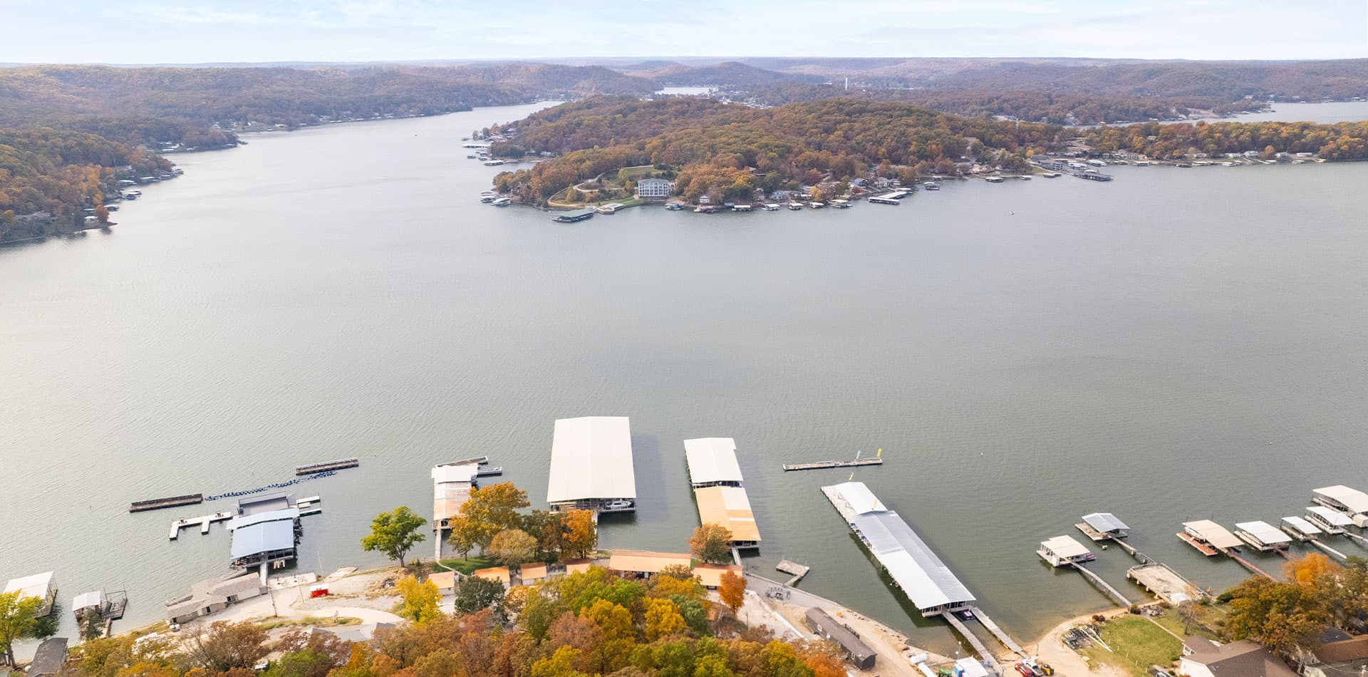 Aerial view of a tranquil lake surrounded by autumn foliage and boat docks.